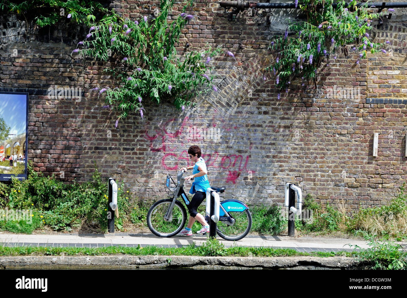 Female cyclist on Barclays Cycle or Boris Bike negotiating chicane installed on the Regent's Canal towpath to slow down cyclists Stock Photo