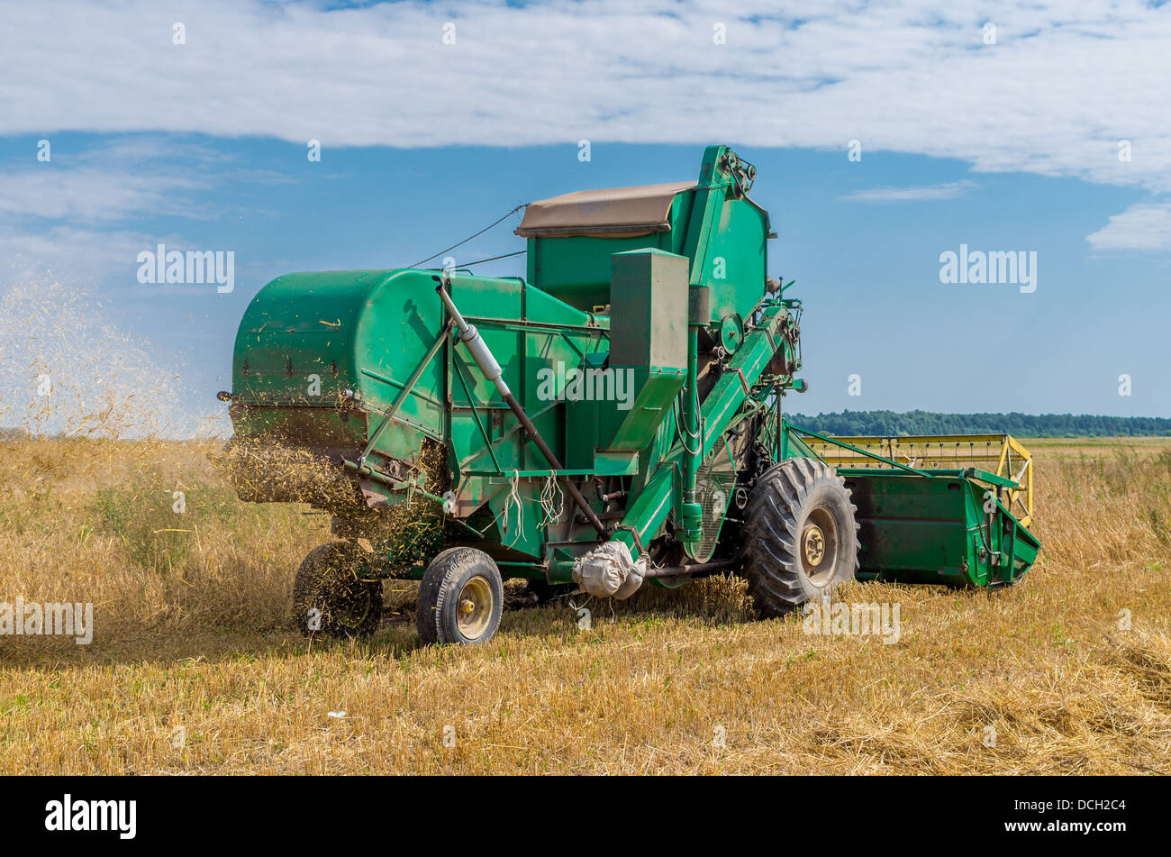 Old grain harvester still working in the field Stock Photo