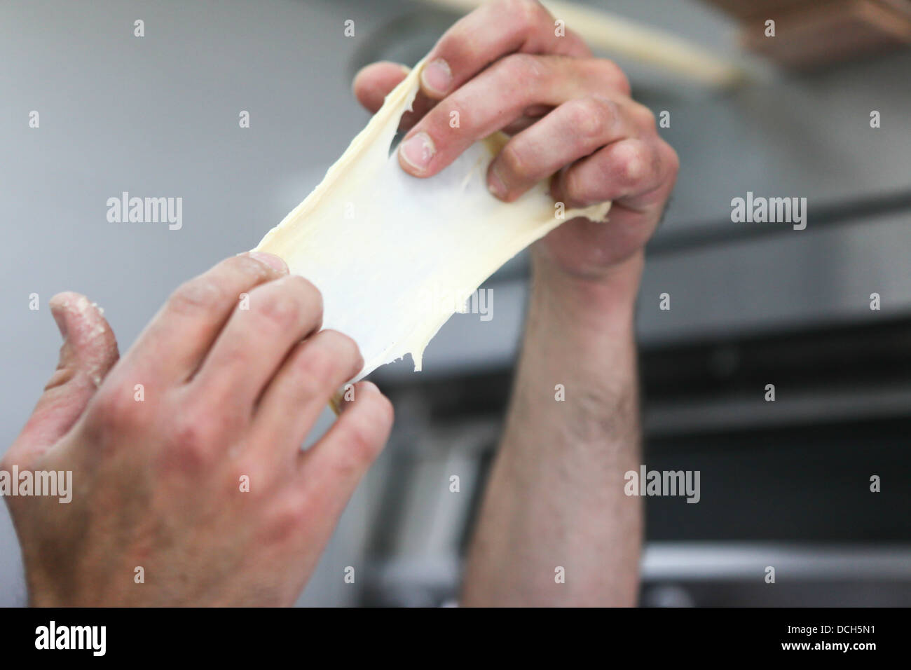 Baking Concept - hands of baker as he inspects the dough Stock Photo