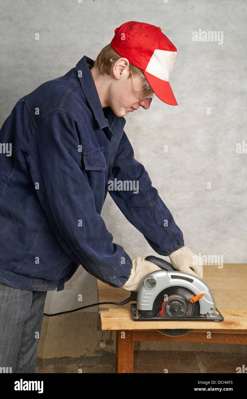 The worker cuts wood with electric circular saw Stock Photo