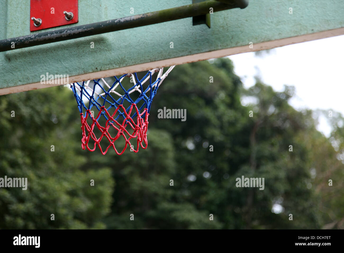 It's a photo of an outdoor basket ball playground with no player. We can see a detail of the basket where players score Stock Photo