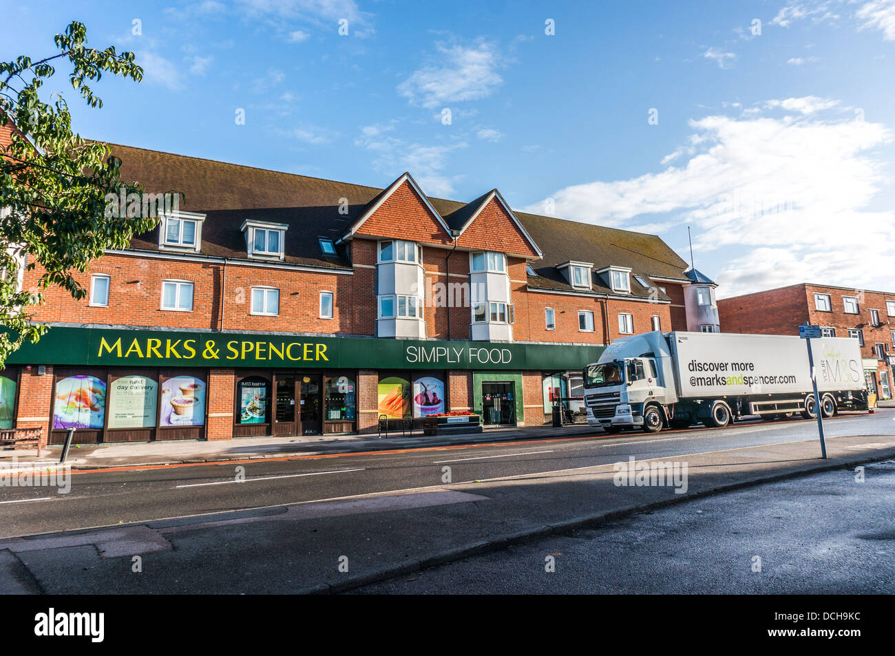 Marks & Spencer (M&S) store / shop with big delivery lorry outside, on Banstead Village High Street, on a quiet Sunday morning in Surrey, England, UK. Stock Photo
