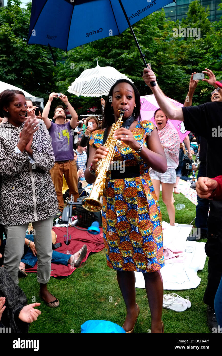 Yolanda Brown Jazz Saxophonist wows the crowds as the rain starts to fall at Canada Square Park, London, UK, 17 August 2013. Stock Photo