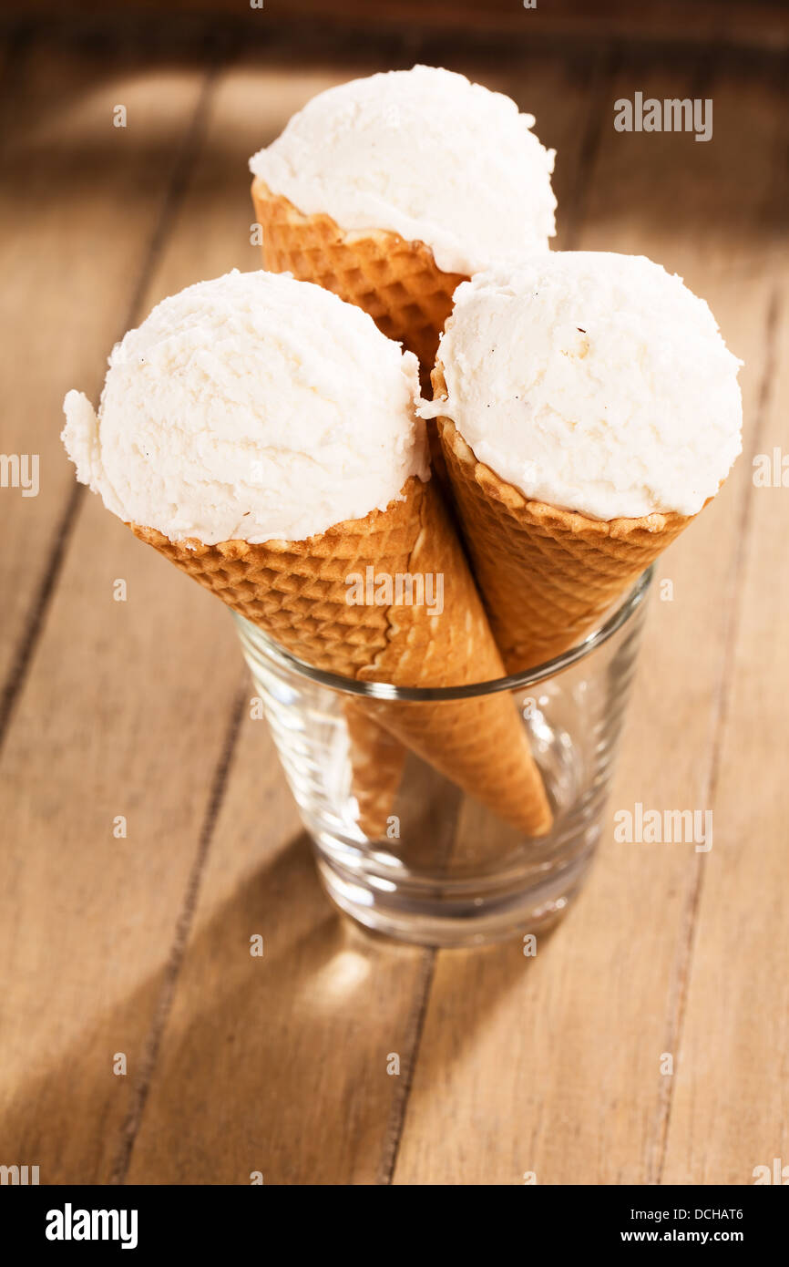 three vanilla ice cream scoops in waffle cones standing in a glass on ...