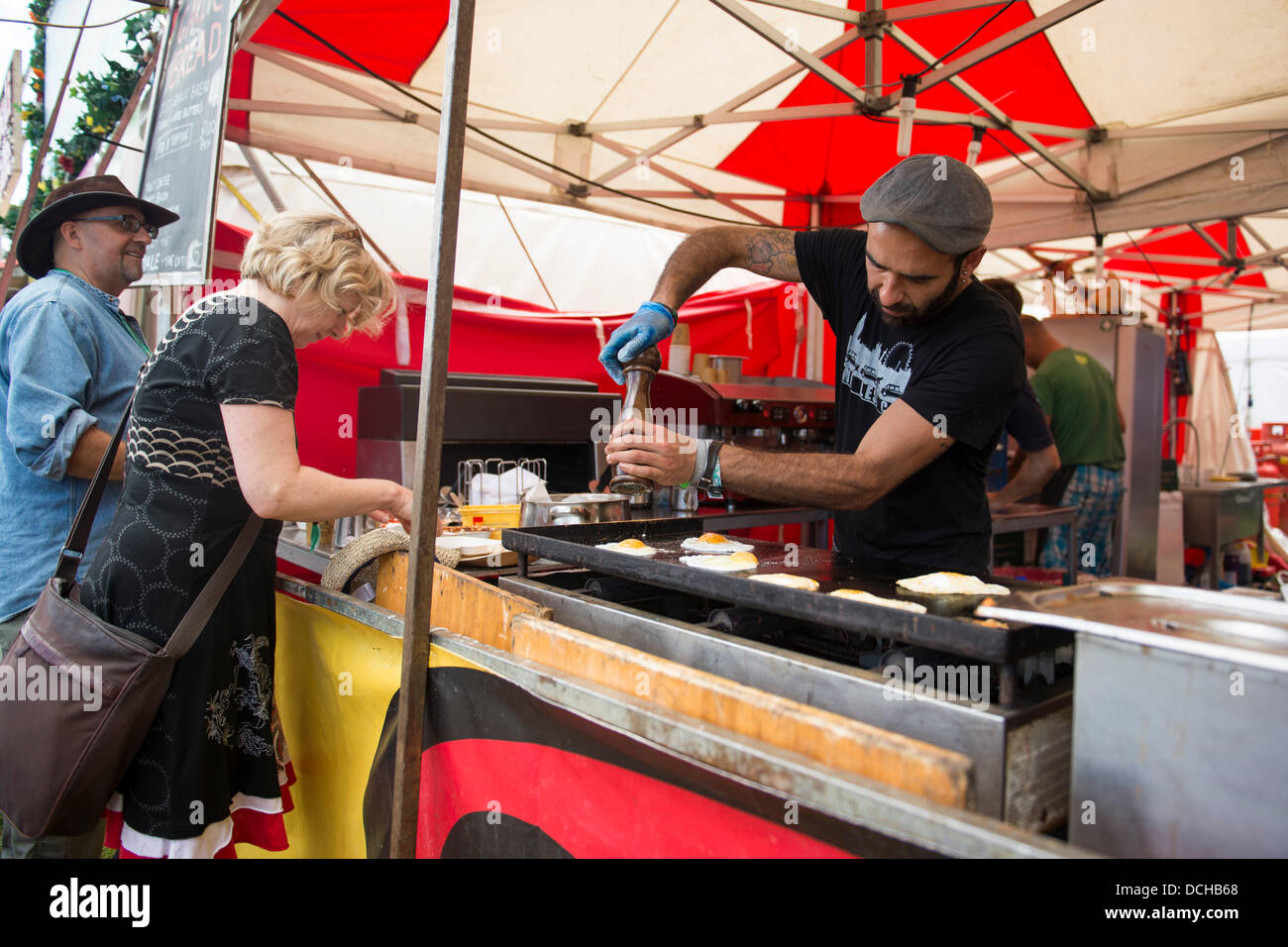 Crickhowell, Wales, UK. 18th August 2013. Day four of Green Man Festival. A food vendor grinds pepper onto cooking fried eggs. Credit:  Polly Thomas/Alamy Live News Stock Photo