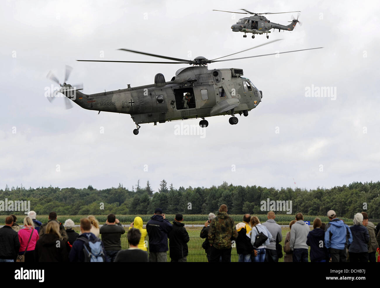 Visitors look at a demonstration by type Seaking and Sealynx helicopters during airday at airfield 'Graf Zeppelin' in Nordholz, Germany, 18 August 2013. The open day at the Bundeswehr's biggest military airfield was organized on the occasion of the 100th anniversary of German Naval aviation. Photo: INGO WAGNER Stock Photo