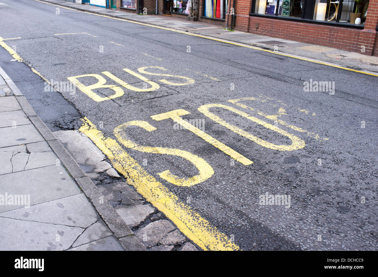 Cracked, faded and worn yellow paint on the tarmac surface of a road at