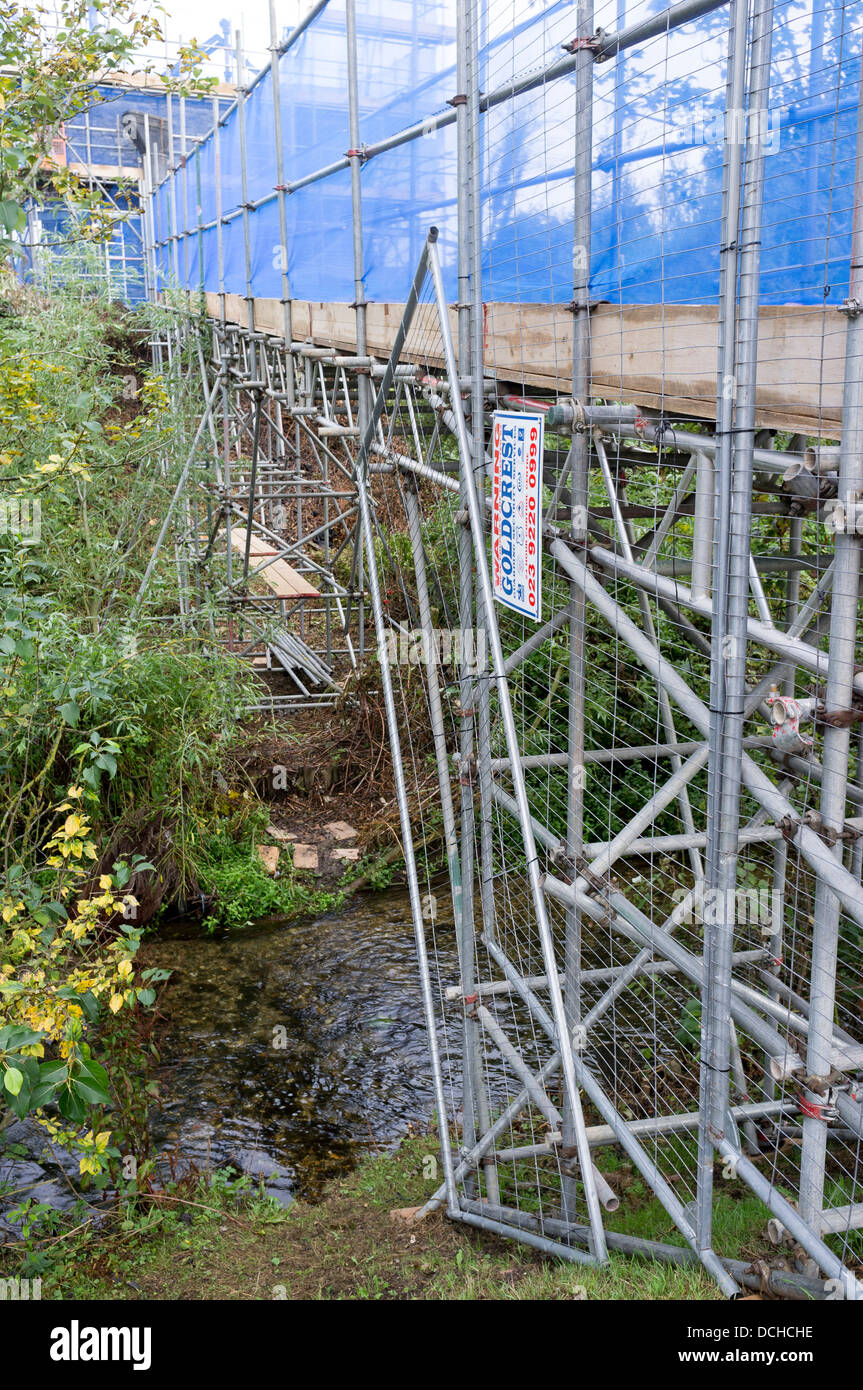 Temporary bridge across UK river constructed out of scaffolding poles with safety netting Stock