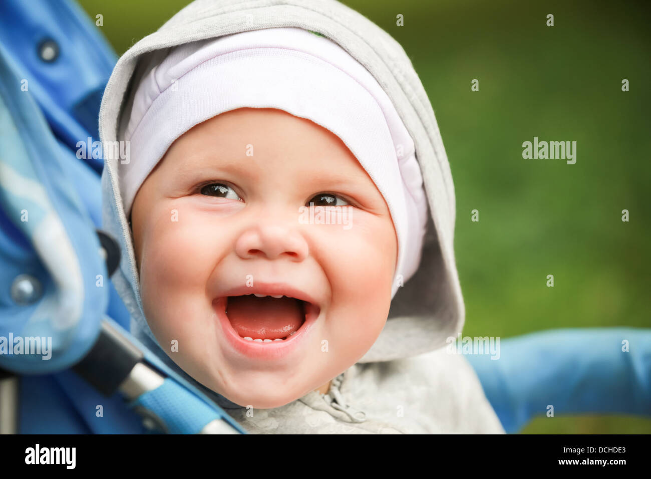Little baby girl laughs in pram on the walk Stock Photo