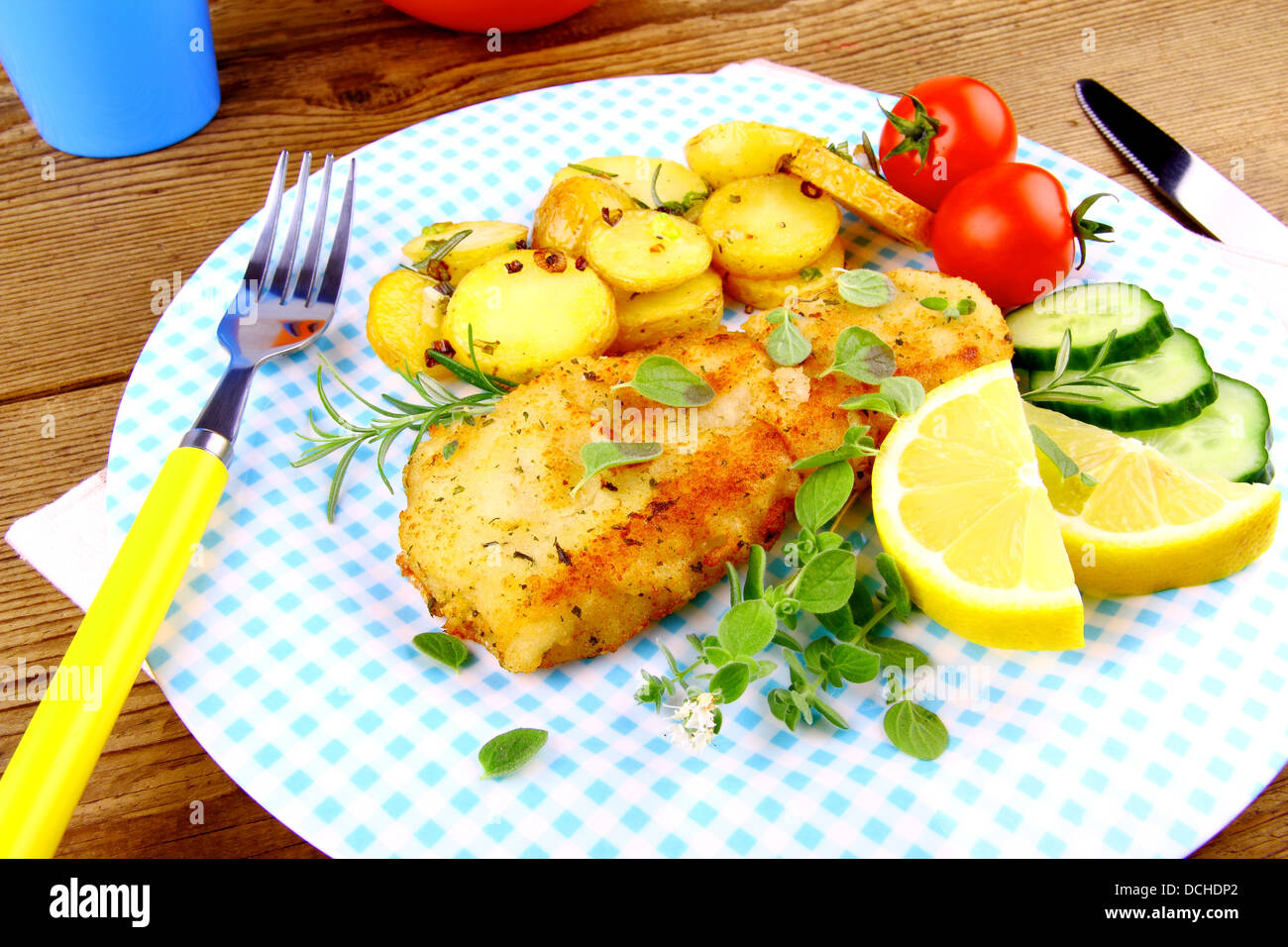 Fried fish fillet with rosemary potatoes and vegetables, close up Stock Photo