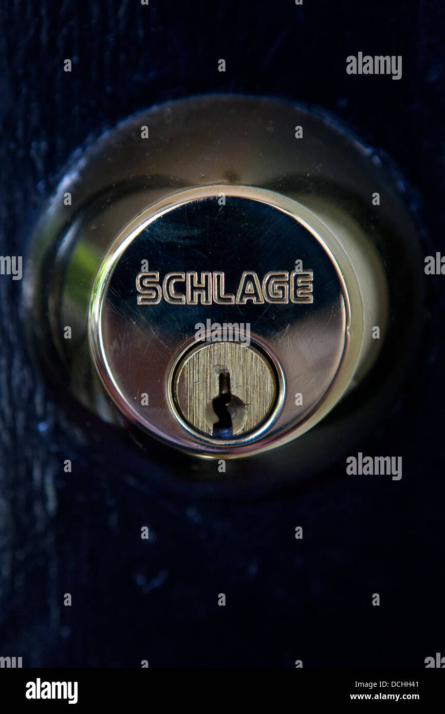 Detailed view of a brass Schlage deadbolt lock on a black door Stock Photo