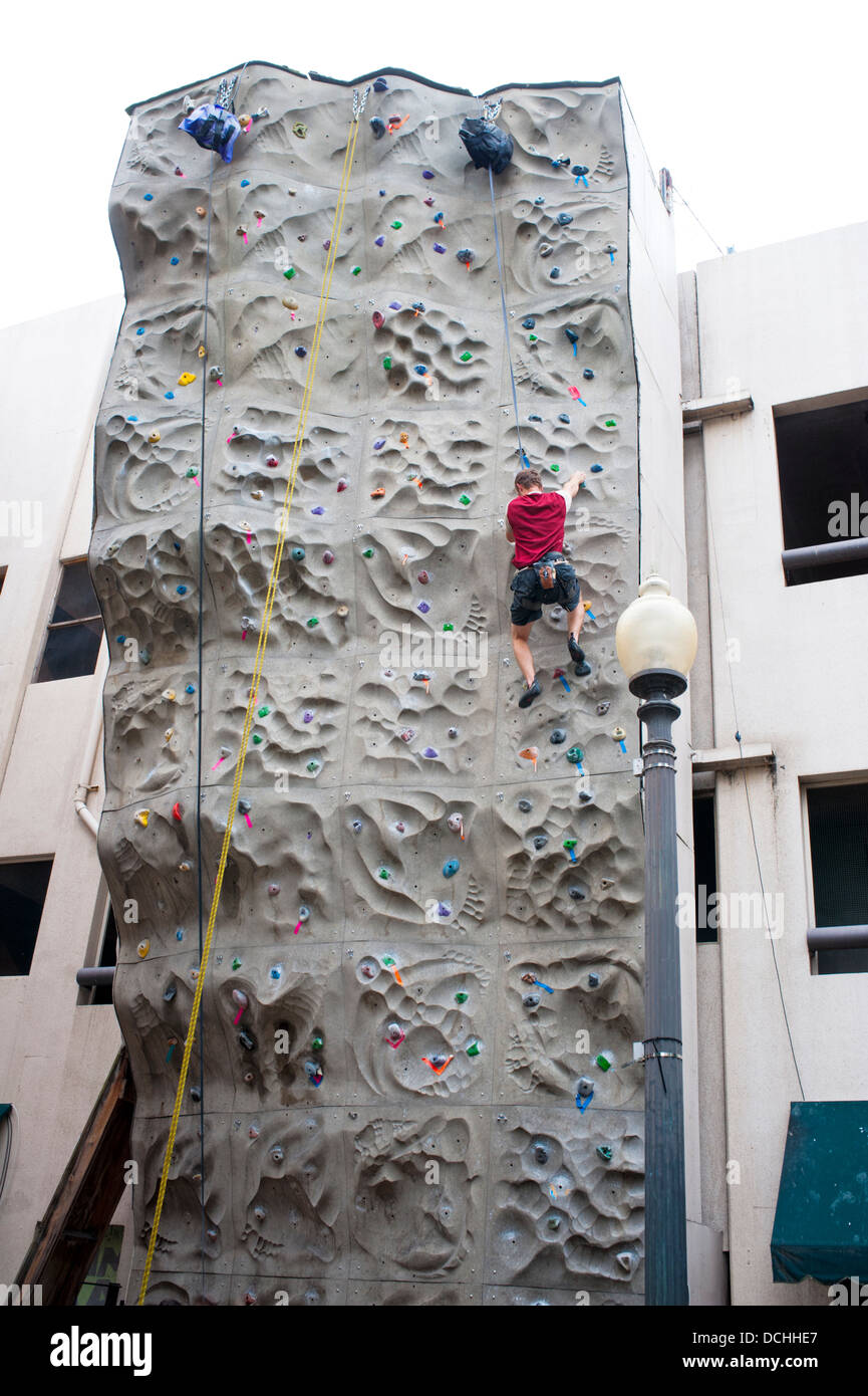 Rock climbing wall with a man nearing the top Stock Photo
