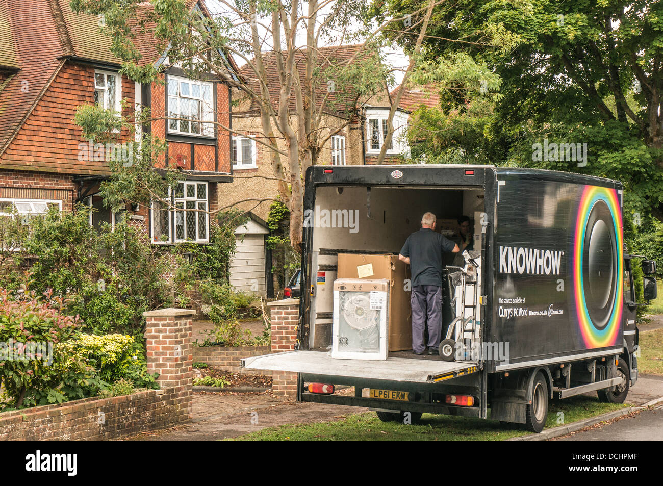 Knowhow - a white goods delivery lorry, with two men inside, parked outside 1930s period houses in a side street of Banstead, Surrey, England, UK. Stock Photo