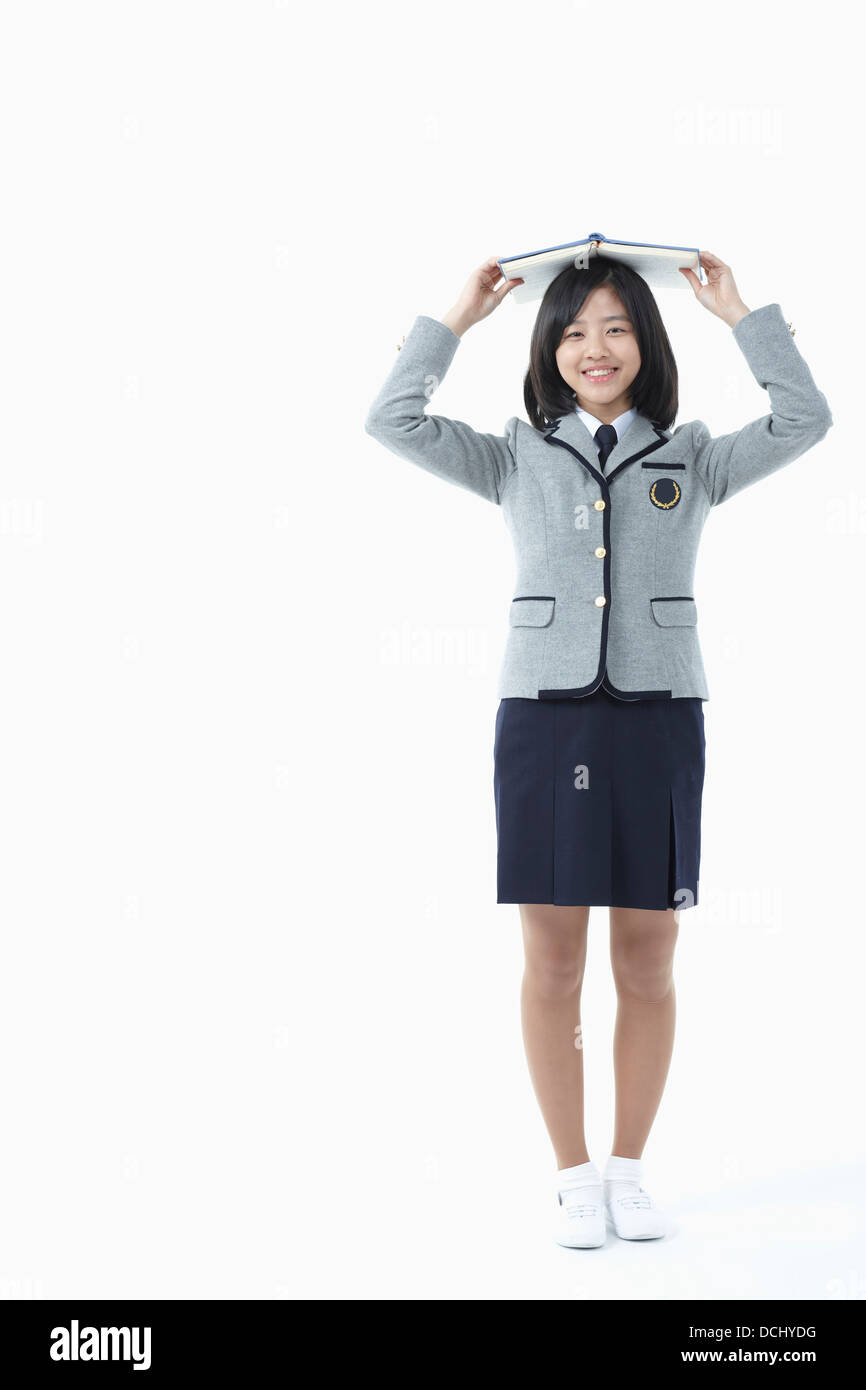 a girl in a school uniform holding a book Stock Photo - Alamy