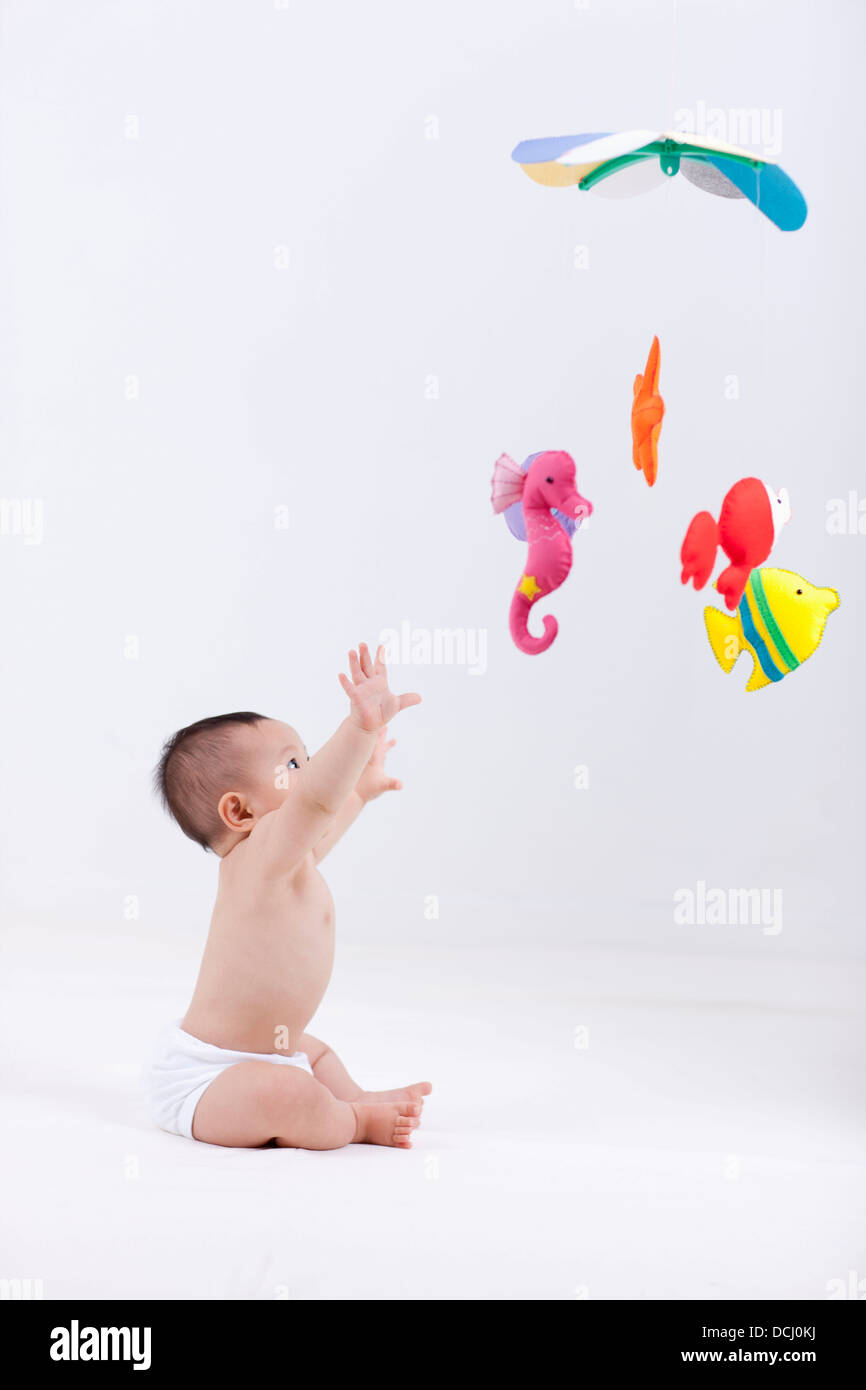 A Baby In Diaper With Mobiles Hanging In The Ceiling Stock
