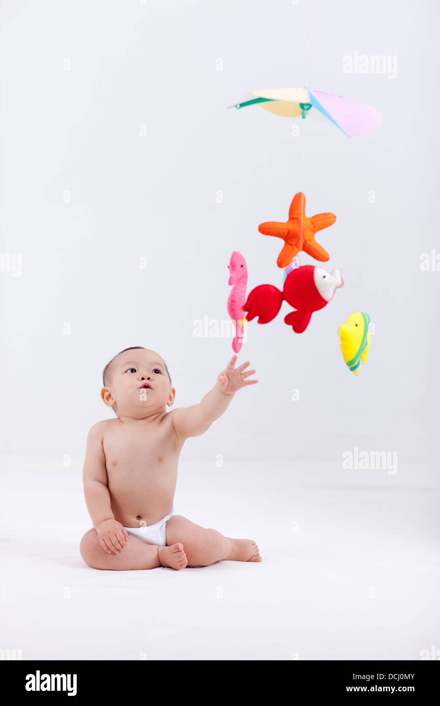 A Baby In Diaper With Mobiles Hanging In The Ceiling Stock