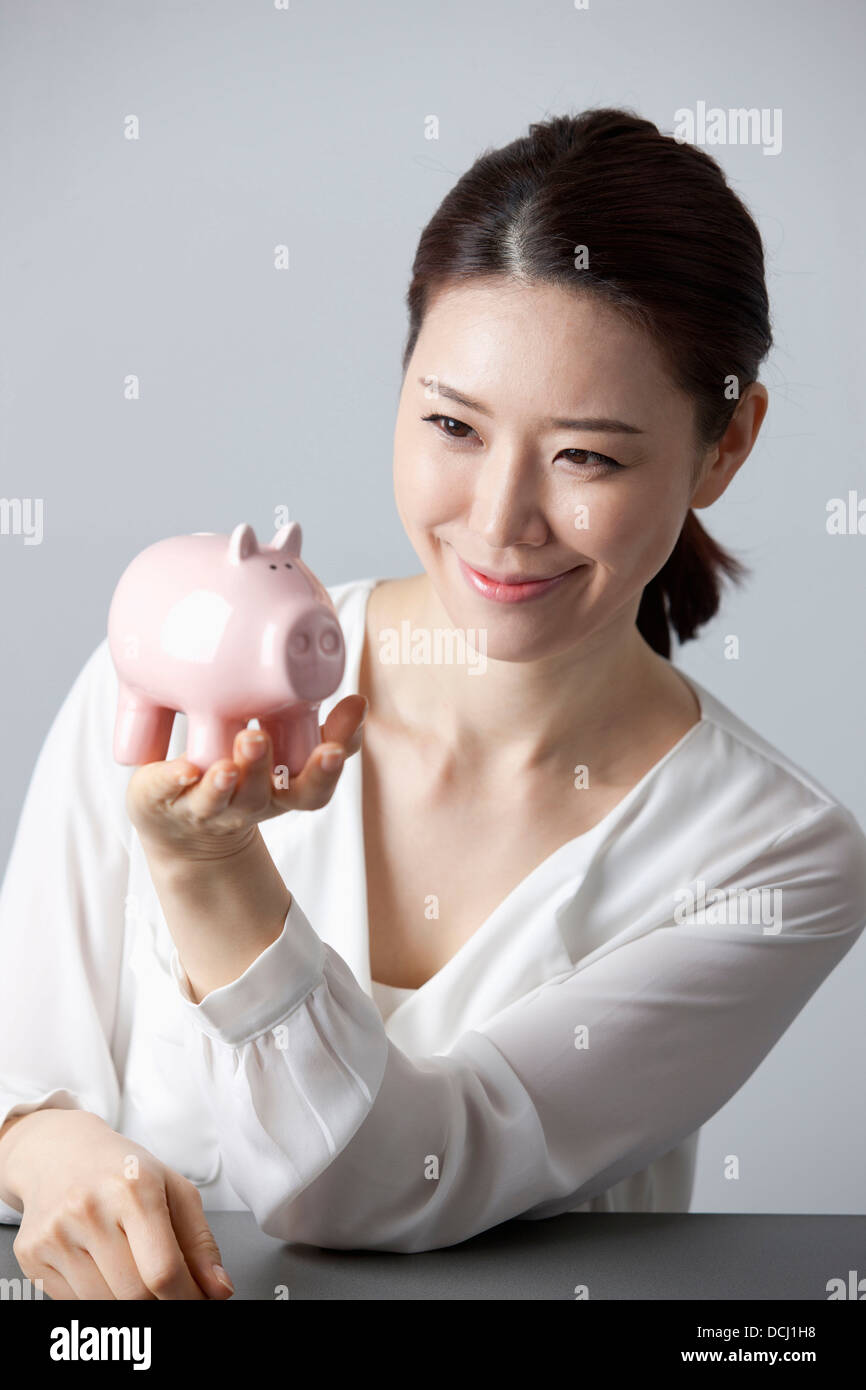a woman smiling while holding a piggy bank Stock Photo - Alamy
