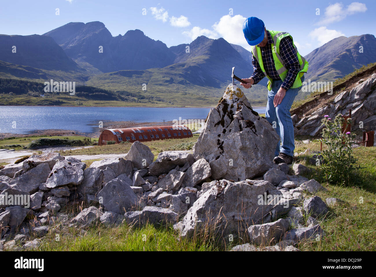 Rock outcrop and Bla Bheinn and Beinn Na Caillich Cuillin mountains; Geologist at Loch Slapin Marble quarry at Ben Suardal, Isle of Skye, Scotland, UK Stock Photo