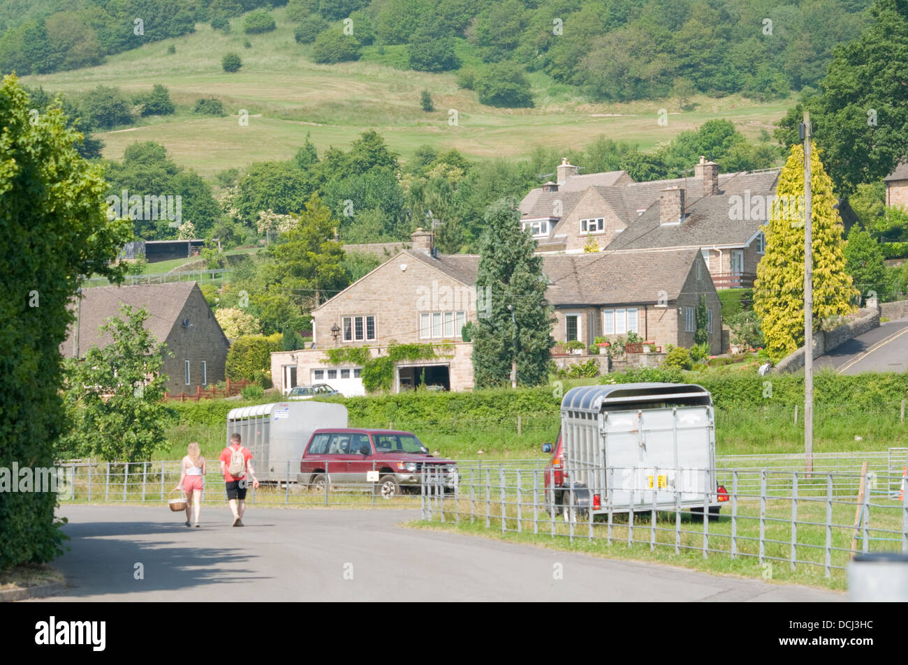 Landscape shot of Bakewell UK, countryside with a couple of people and some houses and two livestock trailers. Stock Photo