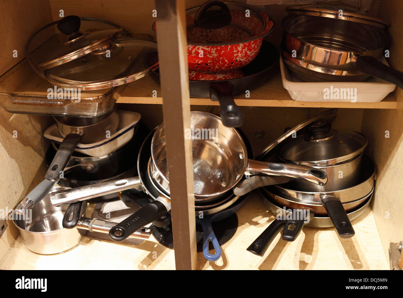 Saucepans in a jumbled kitchen cupbaord. Stock Photo