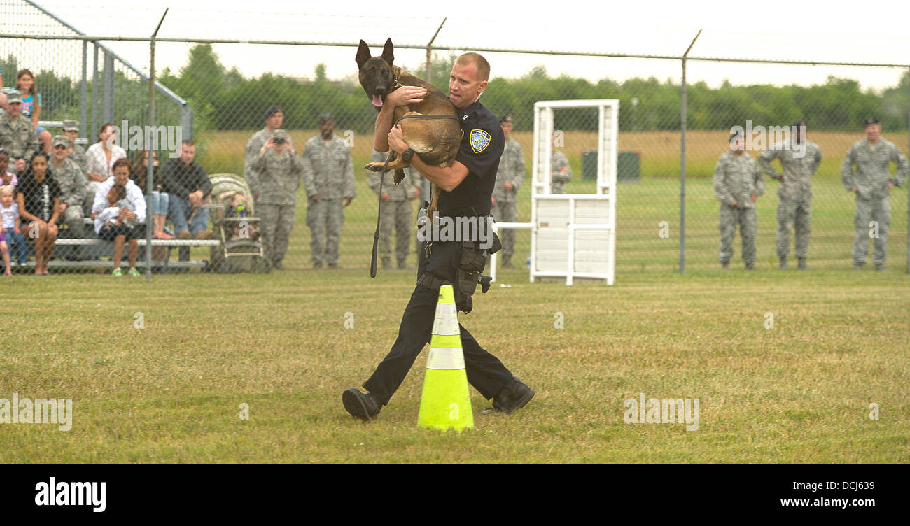 Titus Clouse, a patrolman from the Minot Police Department, carries his 2-year-old K-9, Piko, during one of the many obstacles in the K-9 competition held at the 5th Security Forces Squadron dog kennels on Minot Air Force Base, N.D., Aug. 14, 2013. The 20 Stock Photo