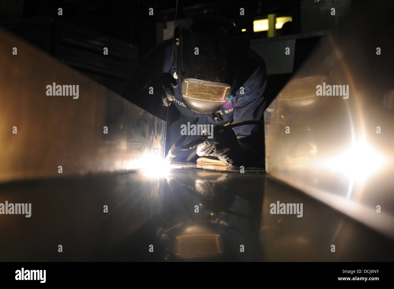 Hull Maintenance Technician 3rd Class Lashod McIntosh, from Portland, Ore., welds an arresting gear cover for the air department aboard the aircraft carrier USS Nimitz (CVN 68). The Nimitz Carrier Strike Group is deployed to the U.S. 5th Fleet area of res Stock Photo