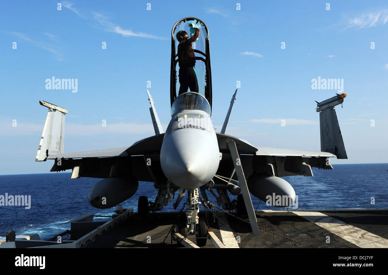 cleans the canopy of an F/A-18F Super Hornet assigned to the Fighting Black Lions of Strike Fighter Squadron (VFA) 213 on the flight deck of the aircraft carrier USS George H.W. Bush (CVN 77). George H.W. Bush is conducting tailored ship's training availa Stock Photo