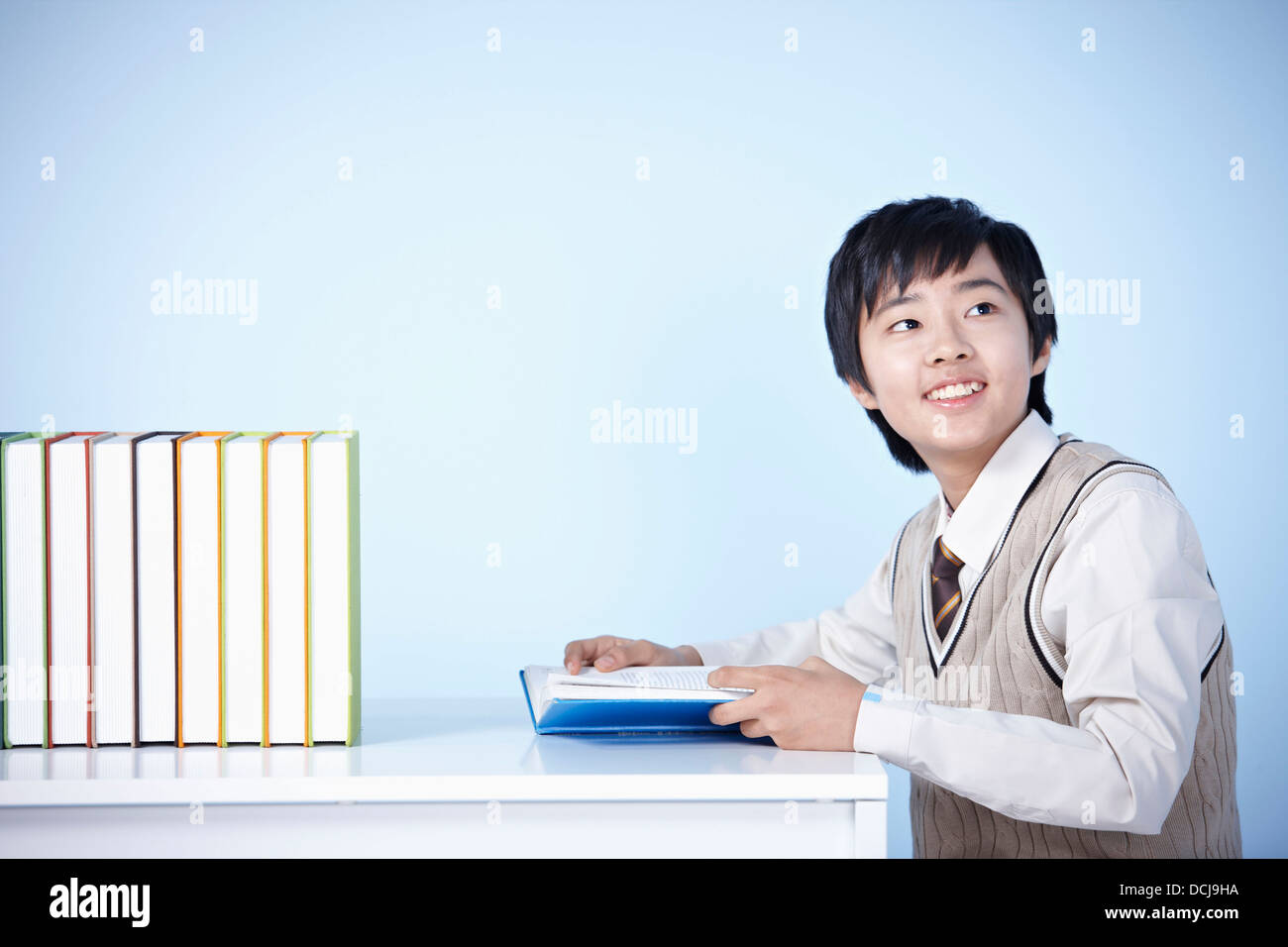 a student in uniform sitting at table reading a book Stock Photo - Alamy