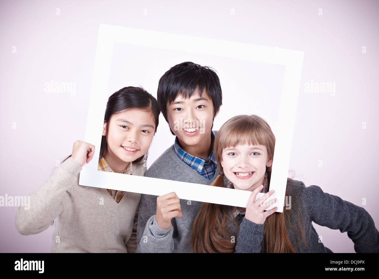 two girls and a boy with empty frame around themselves Stock Photo - Alamy
