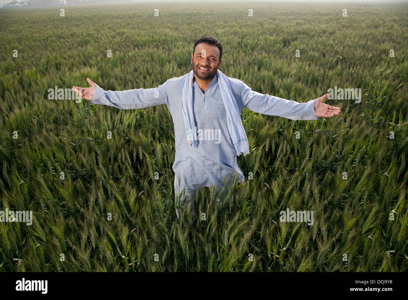 Portrait of an Indian man standing with arms out in a field Stock Photo
