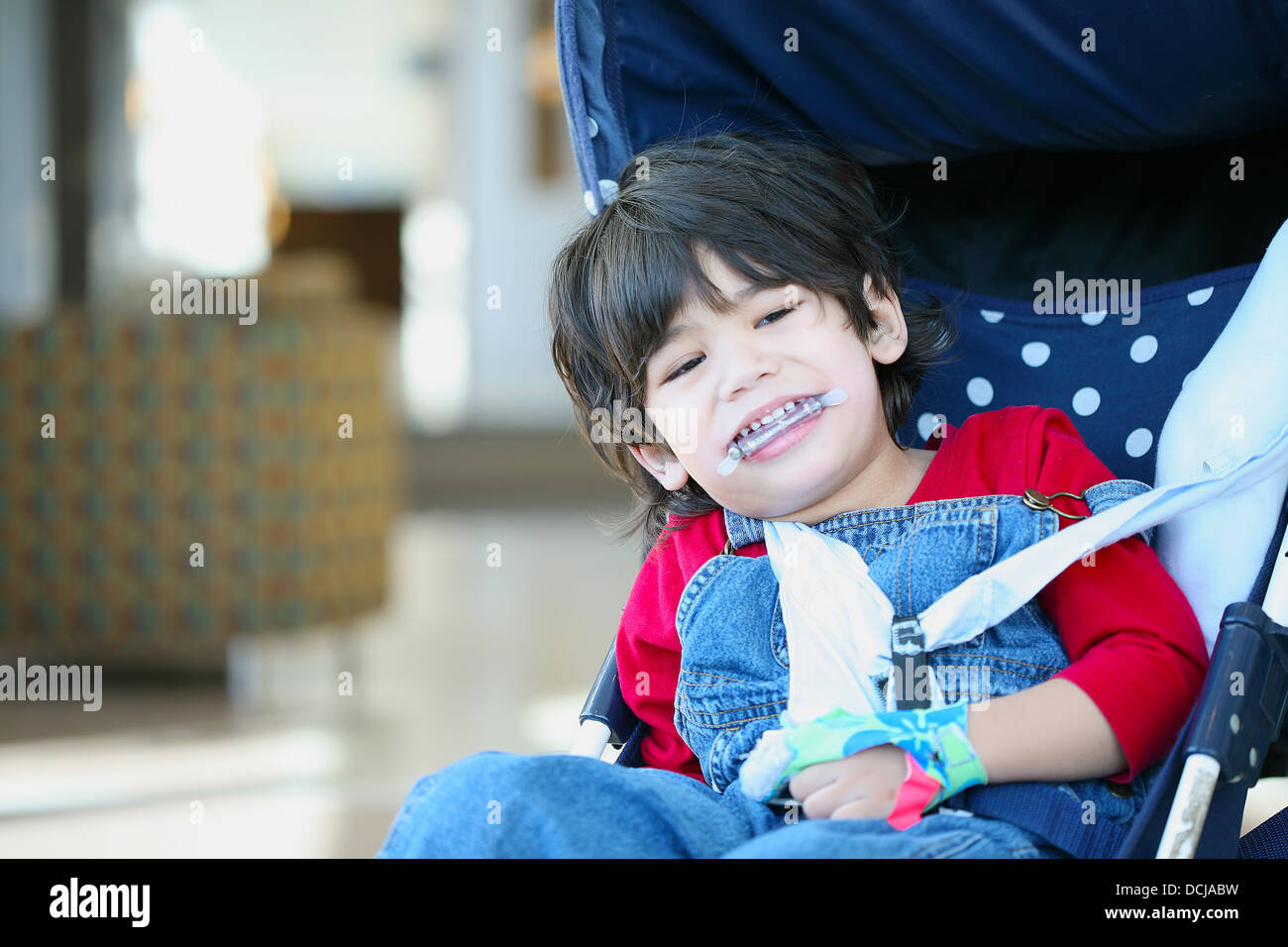 Cute disabled boy with cerebral palsy smiling in stroller Stock Photo