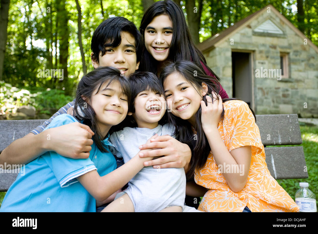 Five kids sitting on bench Stock Photo - Alamy