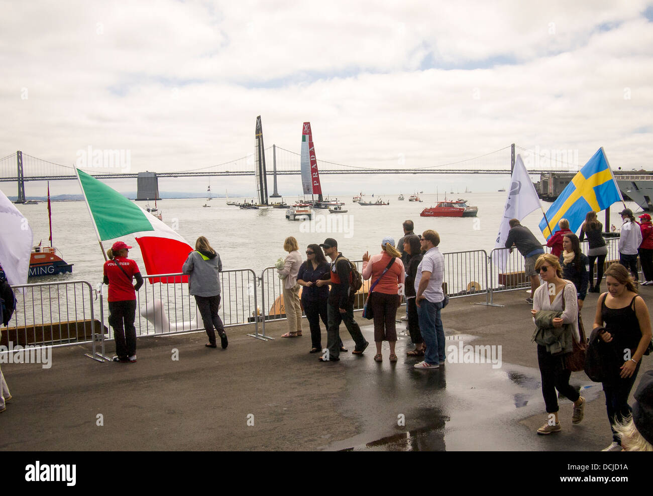 Fans watch a 'fly-by' of Luna Rossa Challenge and Artemis Racing with the San Francisco Bay Bridge in the background Stock Photo