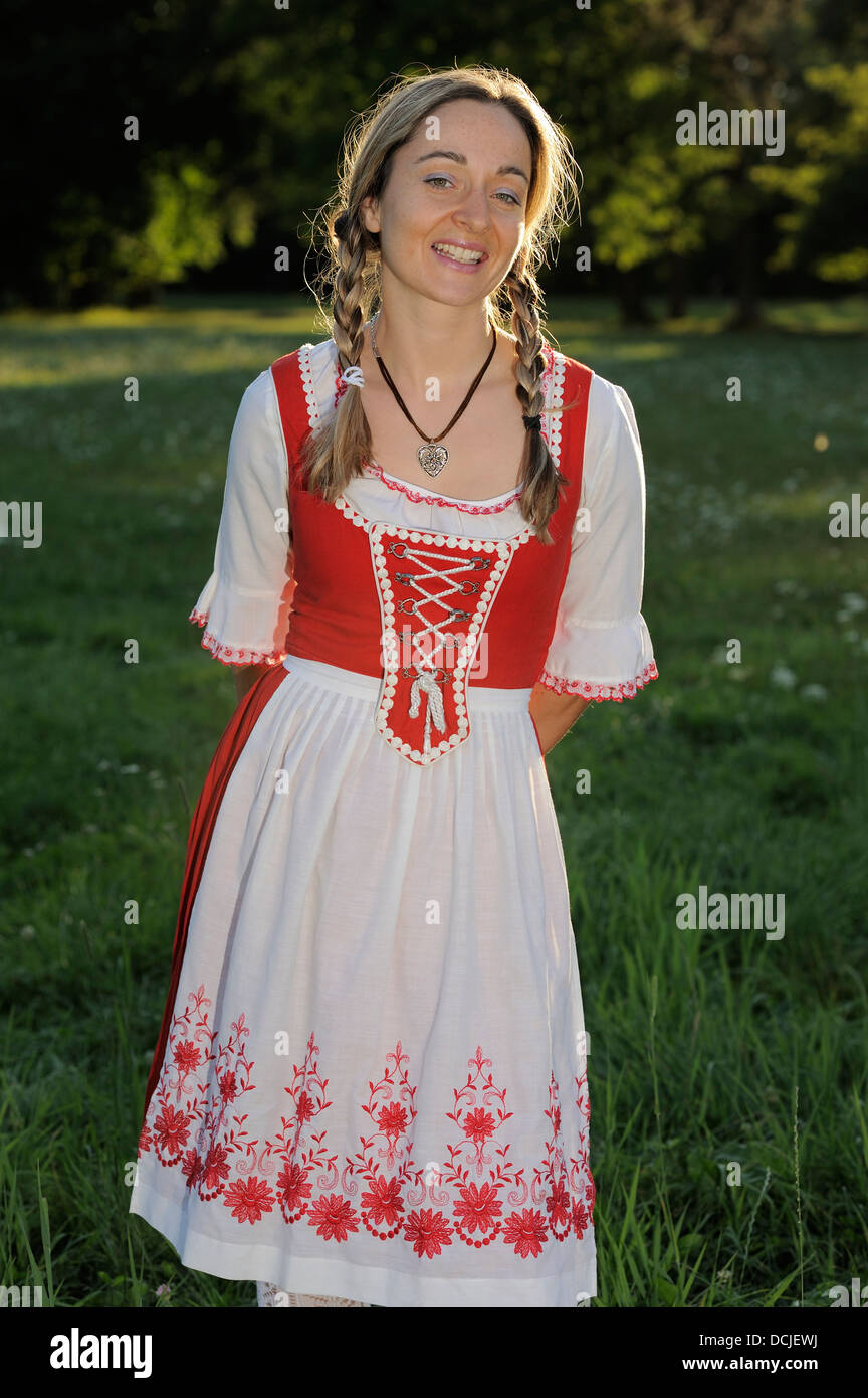 young woman wearing traditional Bavarian dress Dirndl and braids in a park Stock Photo