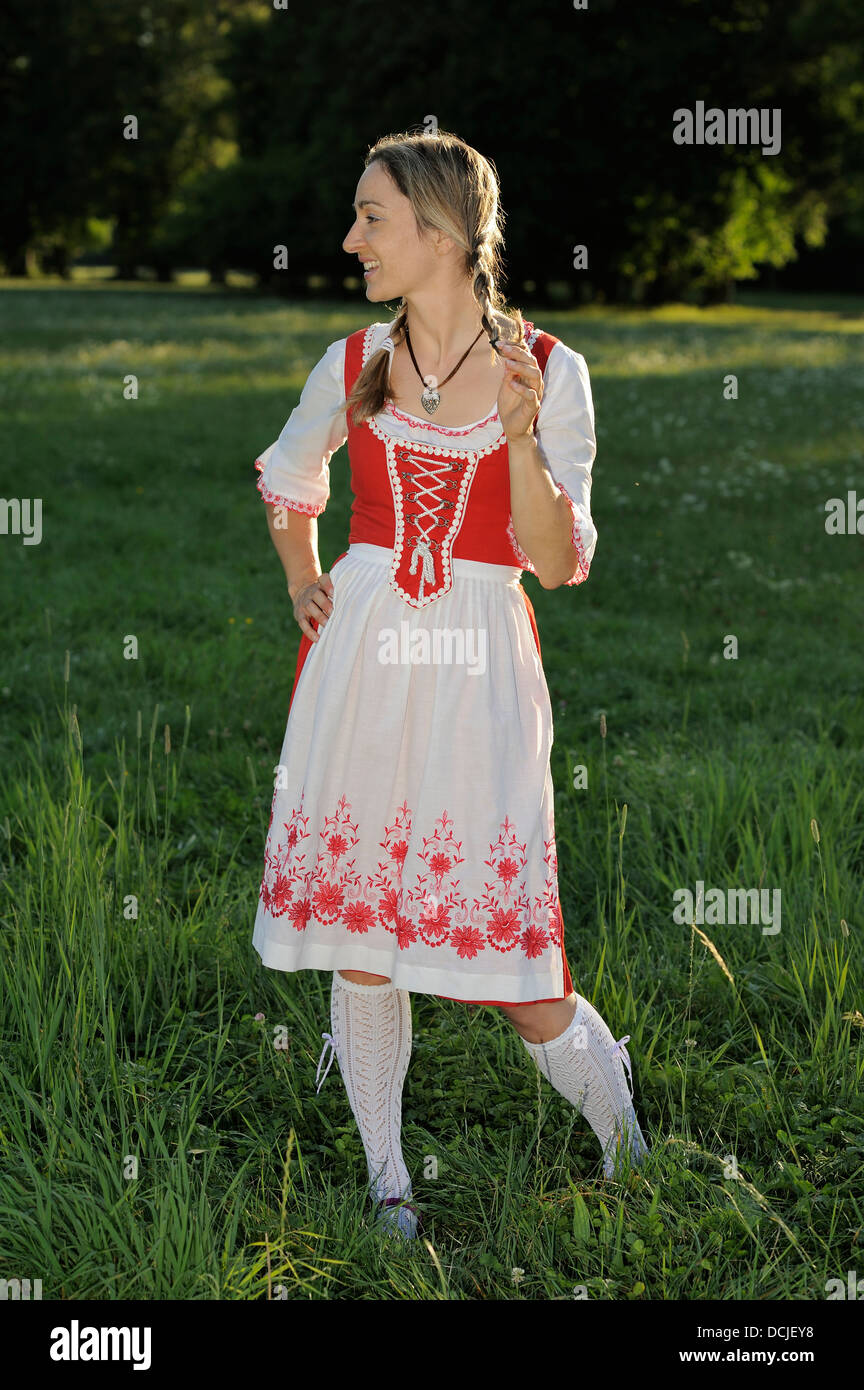 young woman wearing traditional Bavarian dress Dirndl and braids in a park Stock Photo