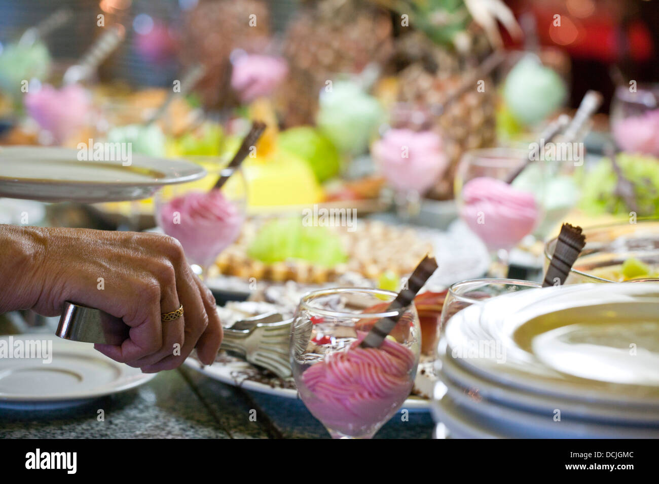 Shallow focus image of person at self sevice sweet buffet/hand of Stock Photo