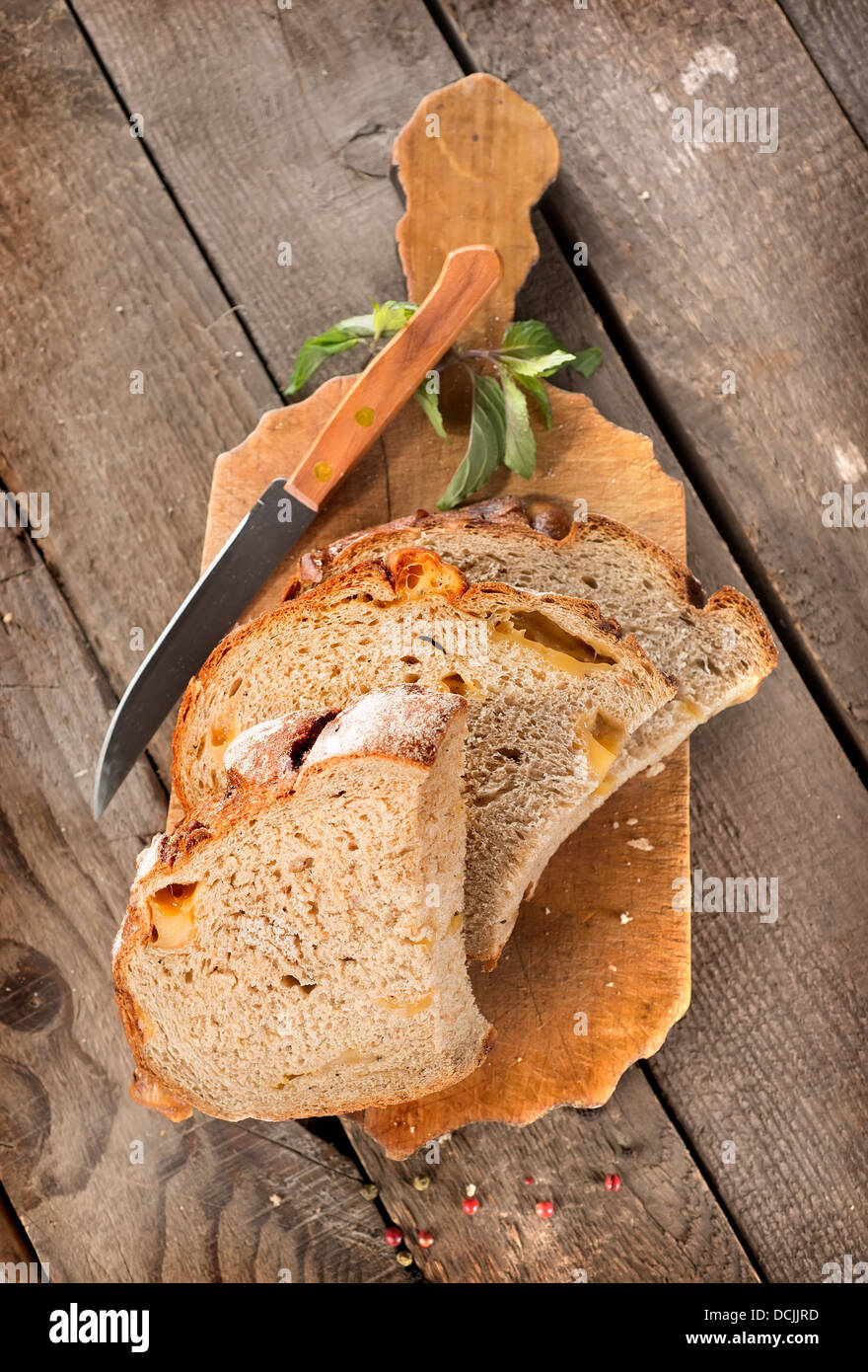 Bread with knife on a cutting board and wooden background Stock Photo