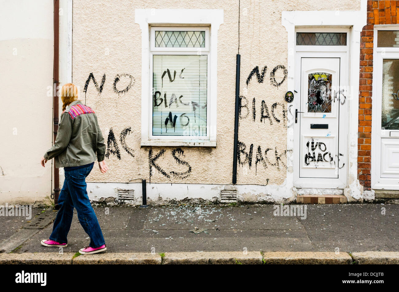 Belfast, Northern Ireland, UK. 19th August 2013 - A woman looks at racist graffiti written on the walls of a house recently occupied by two Nigerian men in Belfast. Credit:  Stephen Barnes/Alamy Live News Stock Photo