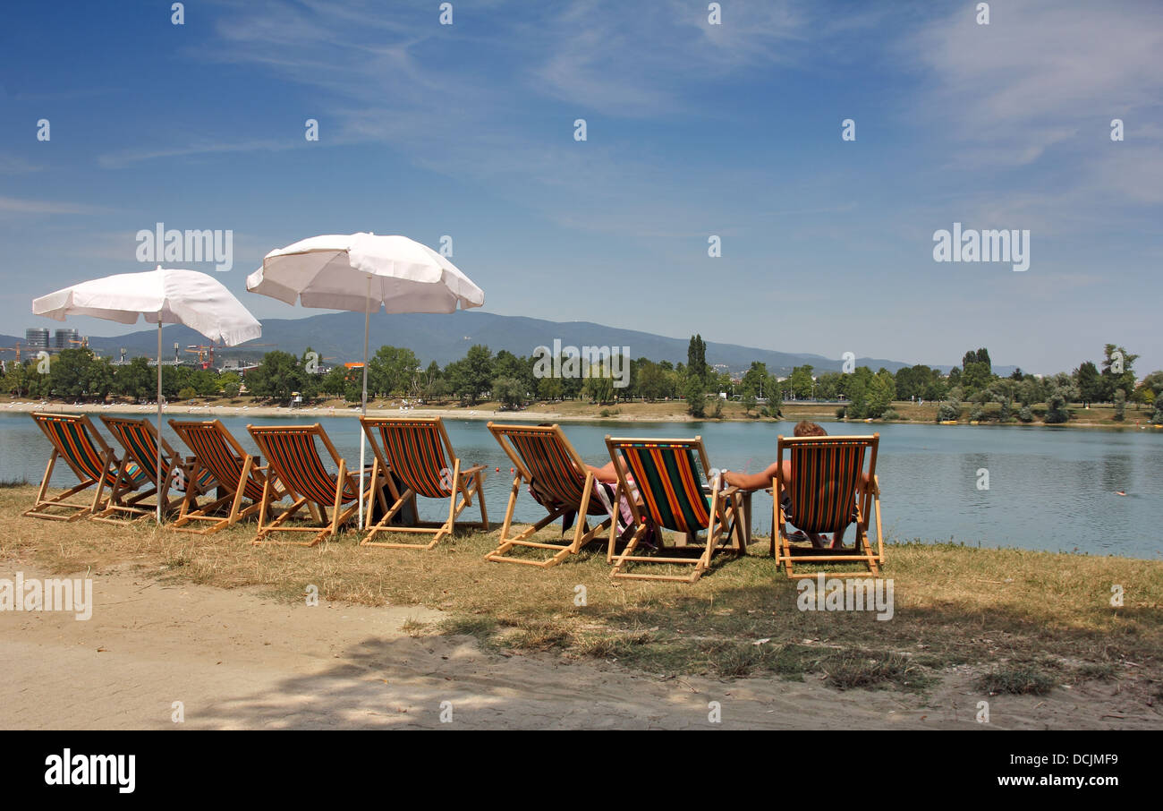 Two young people in colorful deckchairs on the lake shore Stock Photo ...