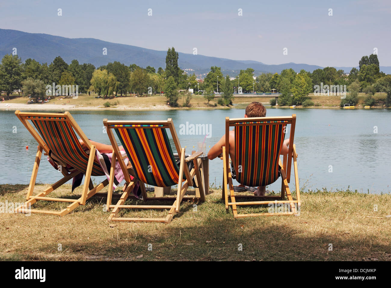 Two young people in colorful deckchairs on the lake shore Stock Photo ...