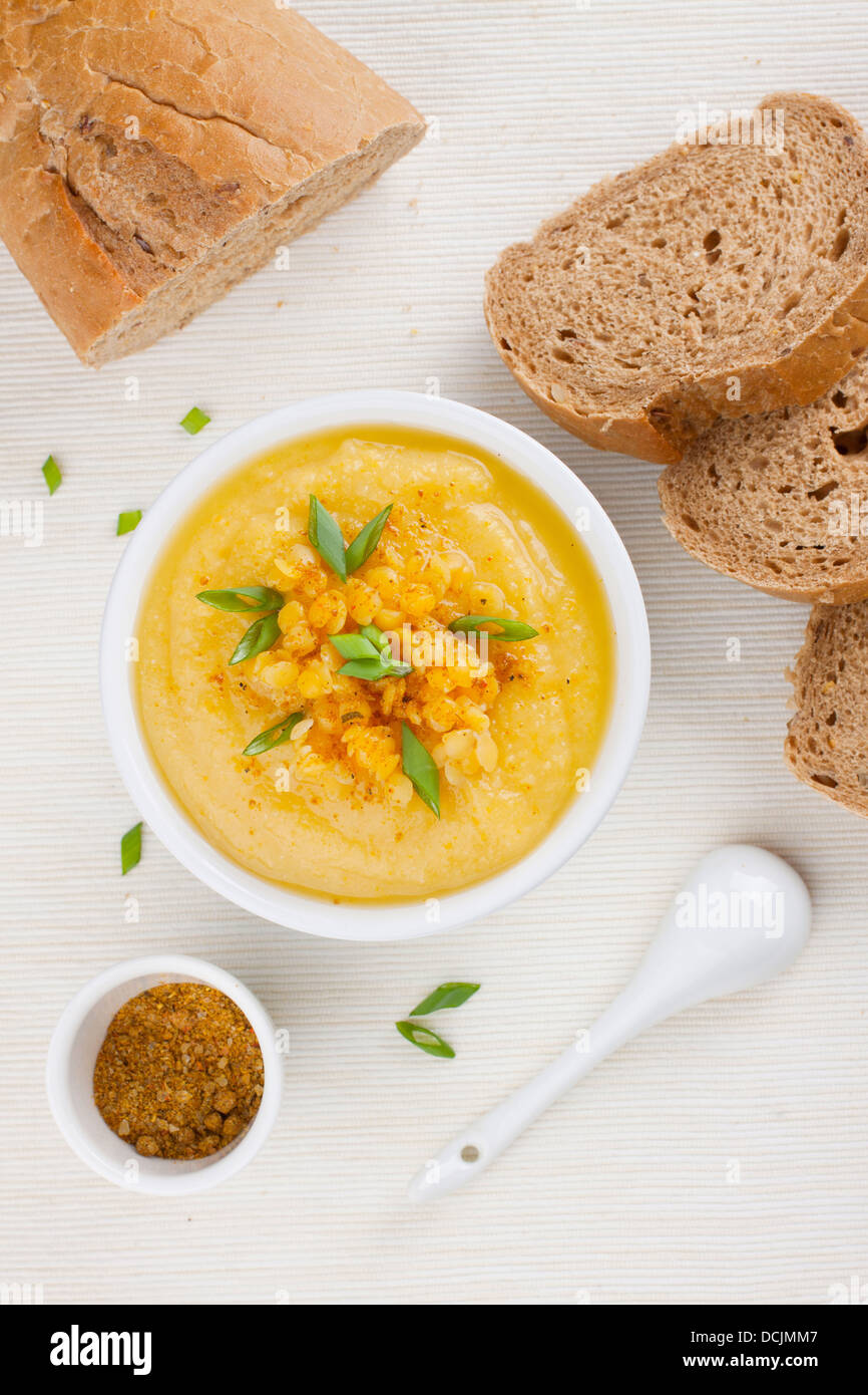 Yellow lentil soup in a bowl, garnished with bright green chives Stock Photo