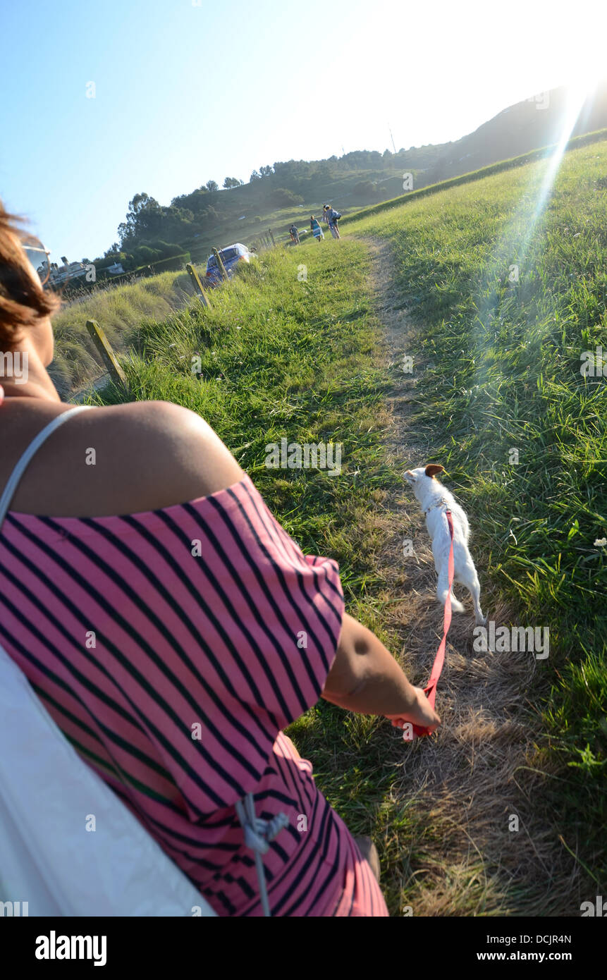 Young woman walks with her small dog in the fields of Niembro, Asturias, Spain Stock Photo