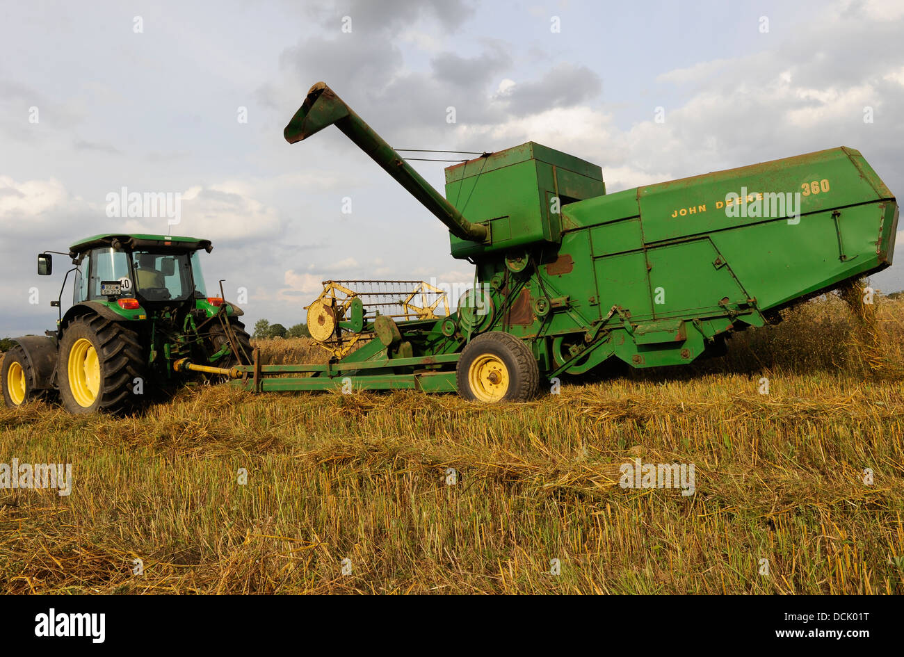 GERMANY old John Deere combine harvester 360 from 1968 pulled by tractor harvesting oats at organic farm Stock Photo