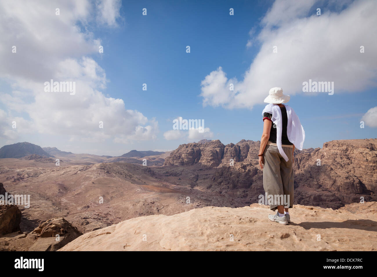 Woman is admiring a view of Jordanian desert while hiking in Petra. Stock Photo