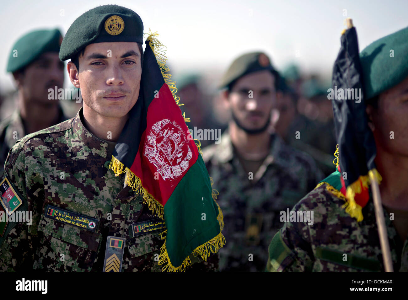 Afghan National Army stand in formation with flags during the national anthem at a celebration marking Afghan Independence Day August 19, 2013 at Camp Shorabak, Helmand province, Afghanistan. Stock Photo