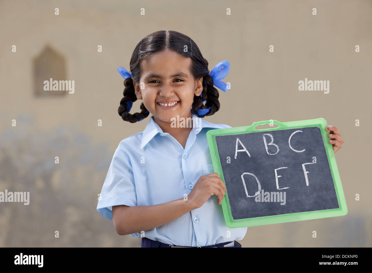 Portrait of a cheerful girl in school uniform holding a slate Stock ...