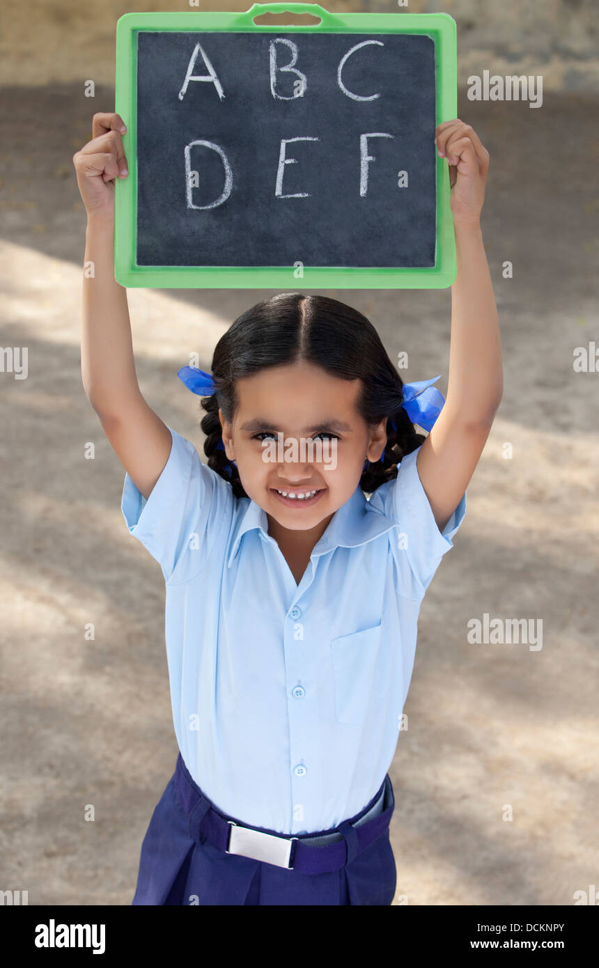 Portrait of a little girl in school uniform holding slate Stock Photo ...