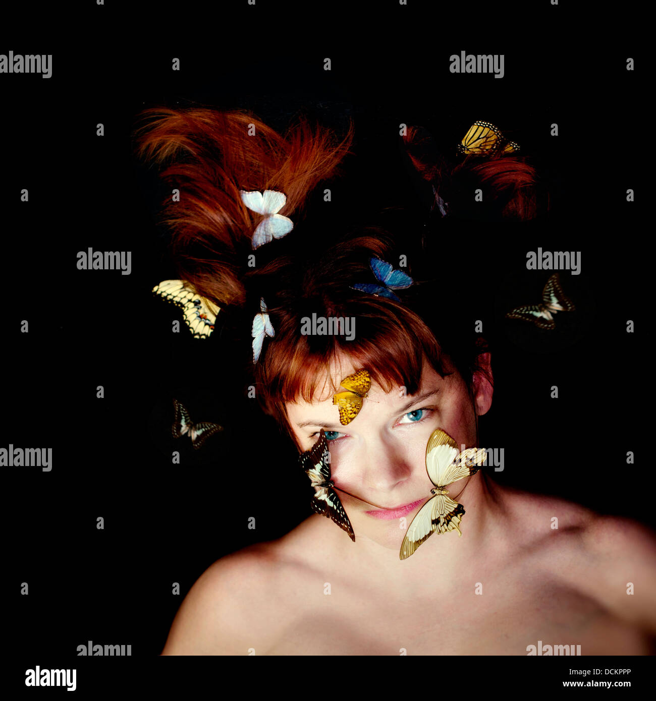 Red haired woman with butterflies on her face and in her hair. Stock Photo