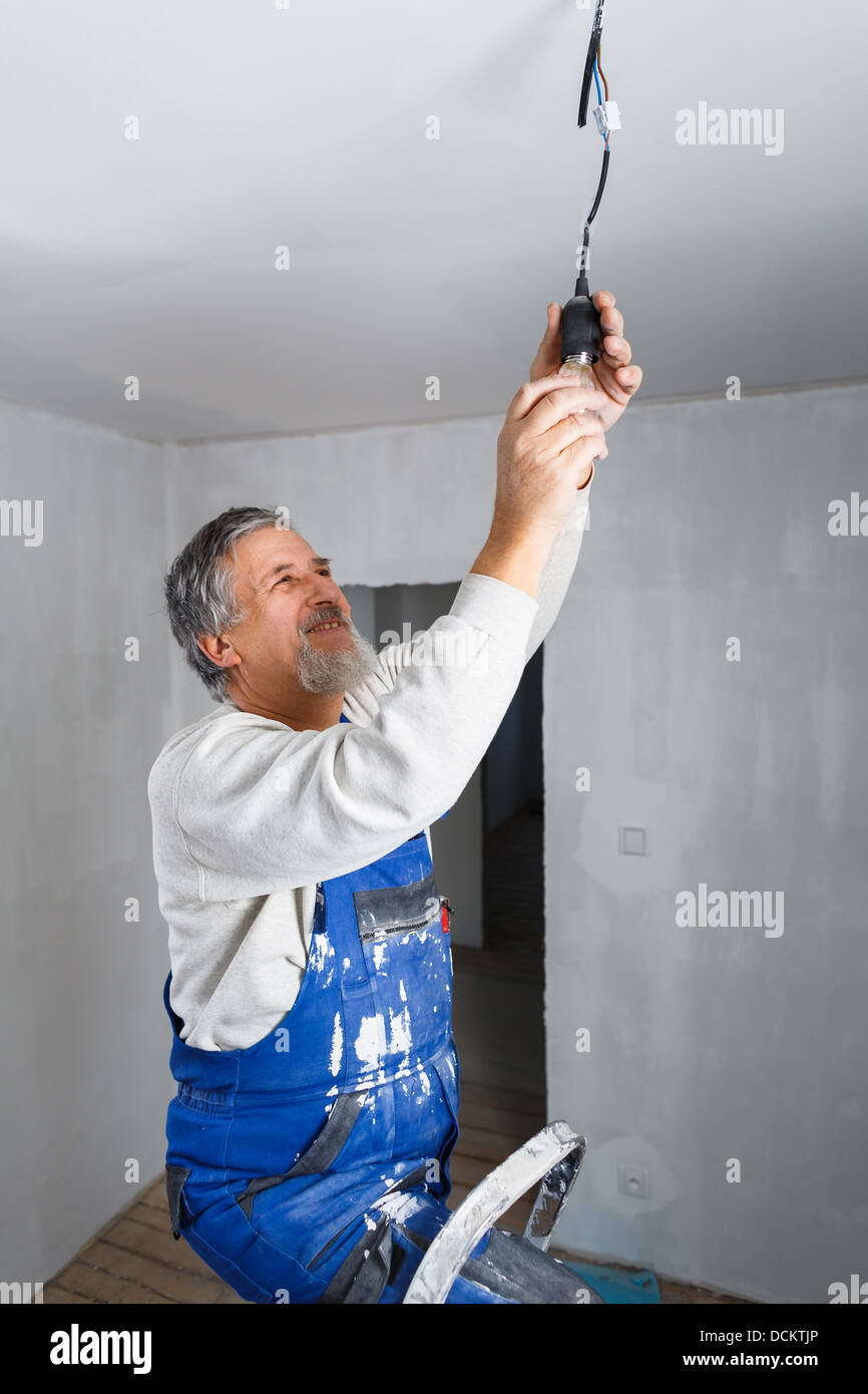 Senior man installing a bulb in a freshly renovated appartment Stock ...