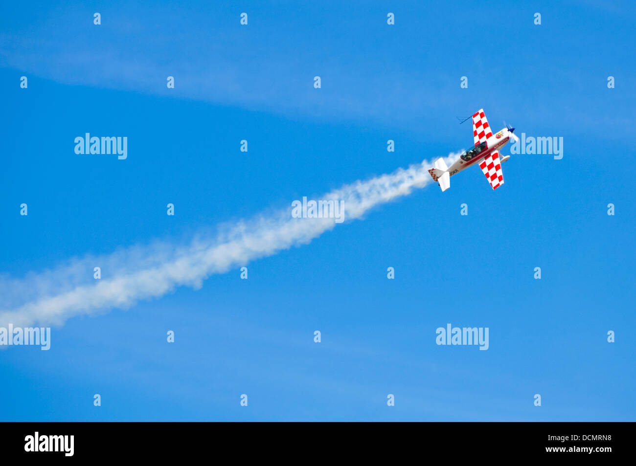 Horizontal view of an aircraft with a vapour trail doing stunts during an air display. Stock Photo